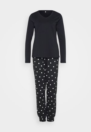 Top de manga larga negro con escote en V combinado con pantalones negros con lunares blancos. Los pantalones tienen puños elásticos y ambos artículos están hechos de una tela suave.