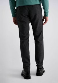 Pantalons à motifs gris foncé avec une coupe ajustée, dotés de deux poches arrière et d'une texture lisse, accompagnés de chaussures en cuir noires.