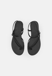 Black sandals with a flat sole, featuring thin adjustable straps and a minimalist design. Material appears sleek with a smooth texture.