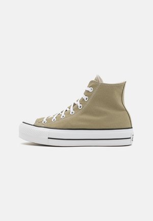 Zapatillas de lienzo de caña alta en verde oliva con acentos blancos, puntera redonda, suela de goma y cordones blancos, que presentan un diseño clásico.