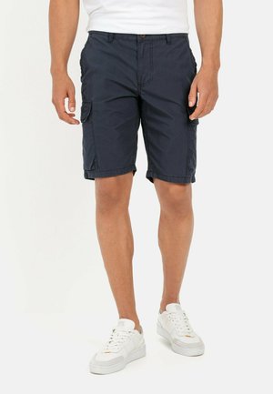 Navy blue cargo shorts made of lightweight fabric, featuring side pockets and a relaxed fit, combined with white sneakers for contrast.