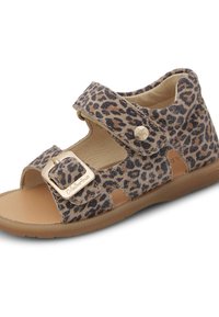 Sandal s leopardím vzorem, hnědým semišovým svrškem, nastavitelnými popruhy a sponou ve zlatém tónu. Plochá podrážka s výřezy pro prodyšnost.
