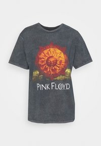 Grå t-shirt med en stor röd och orange solgrafik med ansikte, och texten "PINK FLOYD" i vitt längst ner. Mjuk tygstruktur.