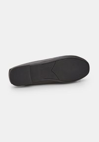 Black shoe sole with a smooth, matte finish and textured grip pattern. Slightly contoured shape with a subtle embossed logo detail.