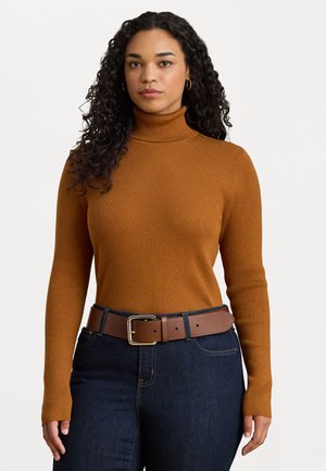 Maglione a collo alto a coste di colore arancione bruciato, con maniche lunghe. Abbinato a una cintura in pelle marrone su jeans di denim scuri.