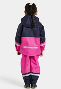 Waterdichte regenjas en -broek in marineblauw en roze met reflecterende strepen. Voorzien van een capuchon, elastische manchetten en een trekkoord in de taille.