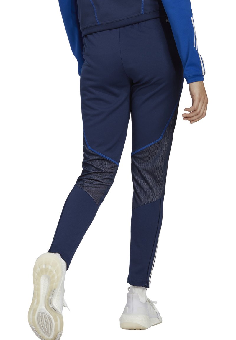 Pantalons de sport navy en tissu extensible, dotés d'accents bleus, d'une coupe ajustée et de jambes fuselées. Comprend des zips aux chevilles pour un ajustement.