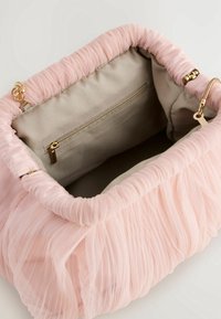 Różowa torebka z falbanami o teksturowanej powierzchni, zamknięta góra i beżowe wnętrze z kieszenią na zamek i złotymi akcentami.