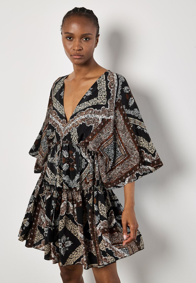 Robe noire longueur genou avec un décolleté en V profond, ornée d'un motif floral et paisley en blanc et marron. Manches courtes et larges, avec une taille froncée.