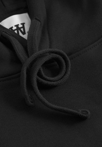 Tissu de sweatshirt noir avec un cordon de serrage torsadé bien visible. La texture est lisse avec une légère brillance, mettant en valeur les détails de confection.