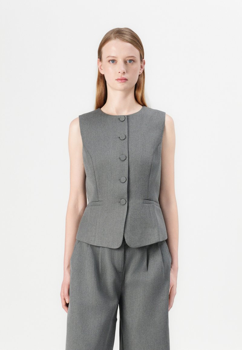 Gilet grigio senza maniche con scollatura tonda, chiusura a cinque bottoni, vestibilità aderente e sottile dettaglio peplum. Fa parte di un completo coordinato.