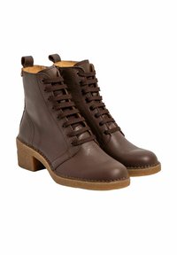 Par de botas de tobillo de cuero marrón con cordones, forradas en tono beige y con suelas gruesas de color marrón claro.