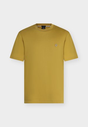 T-shirt jaune moutarde à manches courtes et col rond avec un petit logo circulaire sur la poitrine gauche et une étiquette noire BOSS à l'intérieur du col.