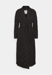 Černý prošívaný dlouhý kabát s límcem, páskem v pase, bočními kapsami a vzorem diamantů po celé ploše. Materiál působí měkce a strukturovaně.