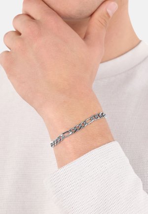 Silberne Metallkette mit ineinandergreifenden Gliedern, die auf einem Handgelenk ruht und eine glänzende Oberfläche sowie eine glatte Textur zeigt.