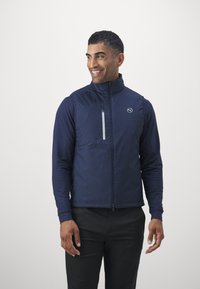 Gilet della marina con colletto alto, chiusura lampo frontale e dettagli riflettenti. Realizzato in materiale leggero, presenta un logo sul petto.