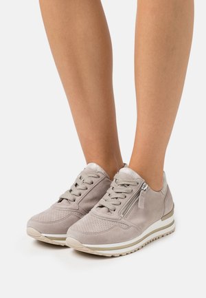 Gray suede sneakers with perforated details, lace closure, side zipper, and metallic accents, featuring a textured white and gold sole.