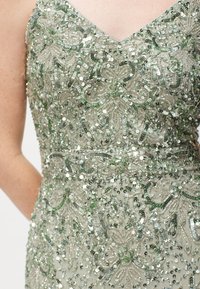 Abito con paillettes e scollatura a V, caratterizzato da un intricato ricamo verde e argento, un corpetto aderente e una finitura luminosa e texturizzata.