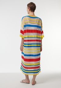 Vestido maxi de tirantes, multicolor y transparente, con franjas horizontales en rojo, amarillo, azul y blanco. Corte holgado con mangas amplias.