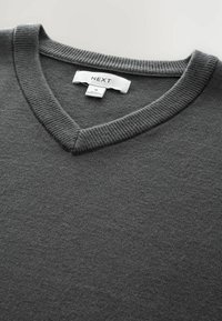 Grauer V-Ausschnitt-Pullover aus weichem Strickmaterial. Verfügt über einen gerippten Kragen und ein Etikett mit der Aufschrift "NEXT" in Größe M.