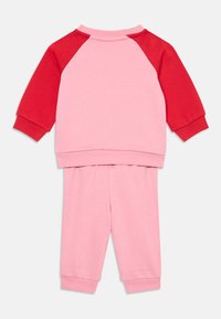 Felpa rosa chiaro con maniche raglan rosse e pantaloni rosa abbinati. Presenta polsini a coste e una morbida trama in cotone misto.