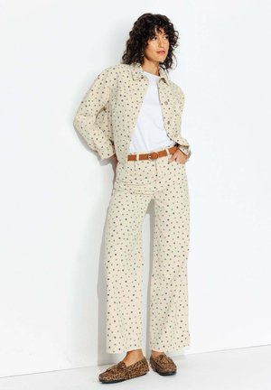 Chemise à imprimé floral beige et pantalon large assorti en tissu léger. Ceinture marron et chaussures à imprimé léopard marron.