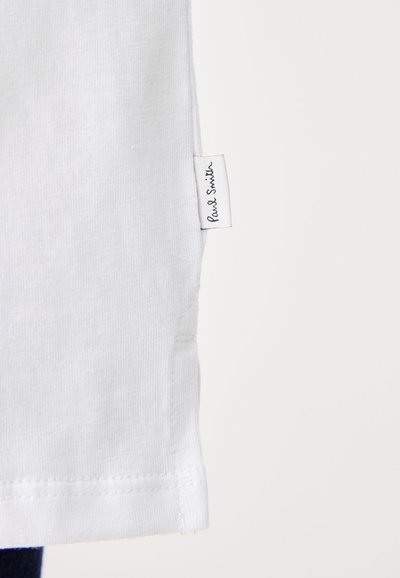 Balts kokvilnas T-krekls ar taisnu apakšmalu, ar diskreto birku, kurā attēlota "Paul Smith" logo kreisajā sānu šuvē.