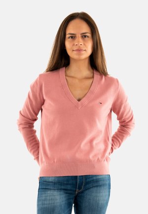 Pull V-neck rose clair en tissu doux, avec des manches longues et un ourlet côtelé. Petit logo sur la poitrine.