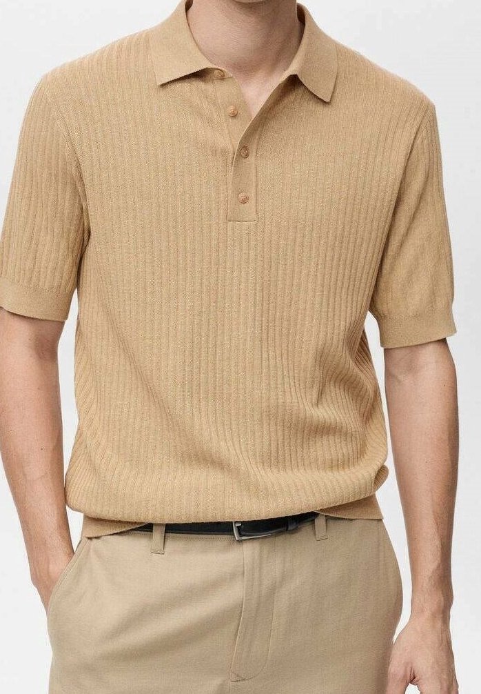 Polo beige à côtes avec des manches courtes, col à deux boutons et tissu texturé, associé à un pantalon beige assorti et une ceinture noire.