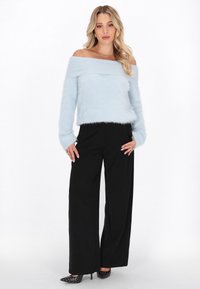 Maglione fuzzy azzurro chiaro, con scollatura a spalle scoperte e maniche lunghe, abbinato a pantaloni neri a gamba larga a vita alta e tacchi neri con borchie.
