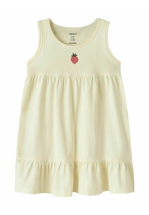 Sleeveless cream toddler dress with gathered waist, ruffled hem, and small red strawberry graphic centered below neckline.