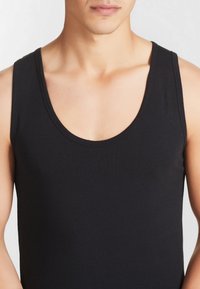 Top senza maniche nero realizzato in un morbido misto cotone, con scollatura rotonda e vestibilità aderente per il massimo comfort.