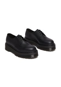 Zwarte leren schoenen met een ronde neus, vetersluiting en een dikke, gestructureerde rubberen zool met een geribbeld patroon.