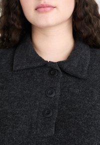 Gray felt shirt with a collar and four black buttons, featuring a textured surface. Close-up of the neckline without additional details.