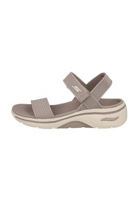 Sandalia beige con tiras cruzadas de malla transpirable. Cuenta con una plantilla acolchada y una suela de goma ligera y curvada.