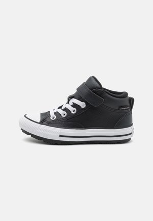 Czarny sneaker typu high-top z białymi sznurówkami i gumową podeszwą, z paskiem na rzep i wodoodporną etykietą z boku.