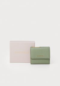 Green leather wallet with textured surface, gold logo, and zip closure. Presented with a light pink box featuring gold text.