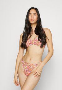 Bikini set with a floral pattern in pink, orange, and yellow. Includes a bandeau top with a front ring detail and low-rise bottoms.