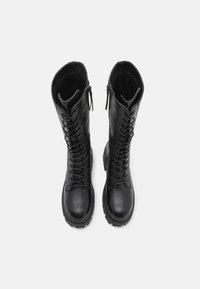 Black leather knee-high boots with a lace-up front and side zippers. Features a chunky sole and smooth texture.