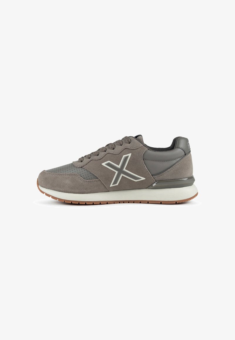 Baskets gris en daim et cuir avec lacets, semelle blanche, bande de roulement marron et logo "X" contour blanc sur le côté.