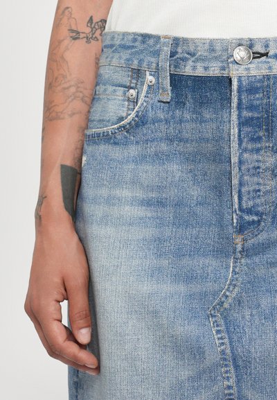 Ljust blå denimkjol med hög midja, frampocket och kontrasterande sömmar. Slät textur med lätt slitage.