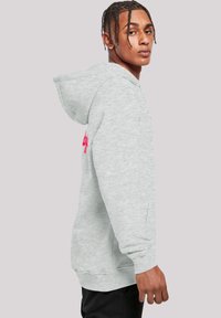 Light gray hoodie made of soft fabric, featuring a kangaroo pocket and ribbed cuffs. Notable pink graphic detail on the left sleeve.