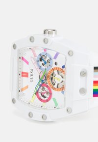 Witte rechthoekige horloge met multikleurige accenten, drie sub-dials en een regenbooggestreepte band. Bevat zilverkleurige hardware en opvallende uurmarkeringen.