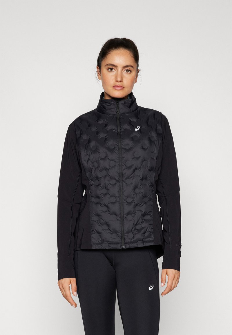 Black athletic jacket with a quilted front, high collar, and long sleeves. Features a zip closure and side panels. Worn with black leggings.