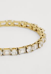 Bracelet en métal doré présentant des cristaux clairs alternant entre carrés et ronds, sertis dans un fermoir à griffes sécurisé, avec une finition métallique lisse.