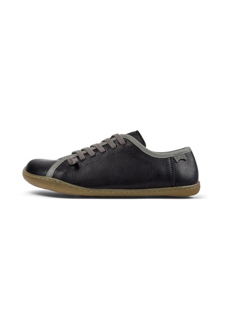 Schwarzer Sneaker mit grauen Schnürsenkeln und Akzenten, der ein minimalistisches Design und eine flexible, leichte Sohle aufweist, seitlich vor einem weißen Hintergrund betrachtet.