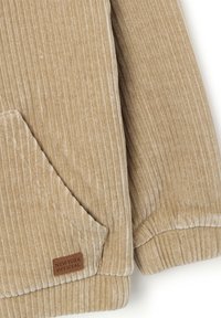 Beige corduroy hoodie met verticale ribbelstructuur, voorzien van een voorzak en een tan leren logo patch met de tekst "NEW YORK OFFICIAL."