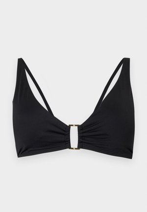 Must rinnahoidja, millel on õhukesed topeltõlapaelad ja väike kuldne ristkülikukujuline klamber, mis ühendab ees keskel voltis kangast.