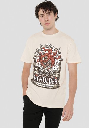 Cremfarbener Baumwoll-T-Shirt mit einem detaillierten Grafik eines roten Beholder-Monsters mit mehreren Augen und Schädeln, gedruckt in Schwarz und Rot.
