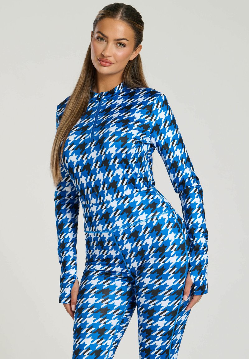 Blauw houndstooth-patroon actieve kleding met lange mouwen en een hoge kraag, met een rits en een strakke fit. Gemaakt van rekbare stof.